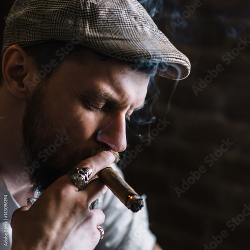 A young bearded man smoking a cigar in a pub