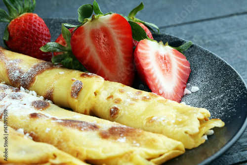 Crepes with jam, strawberries and sugar powder. Homemade pancakes, delicious breakfast