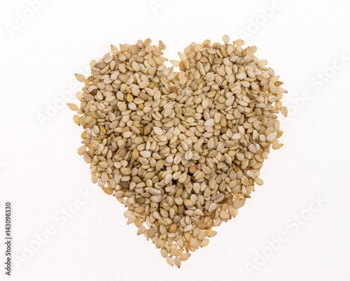 Sesame seeds in the form of heart on white background