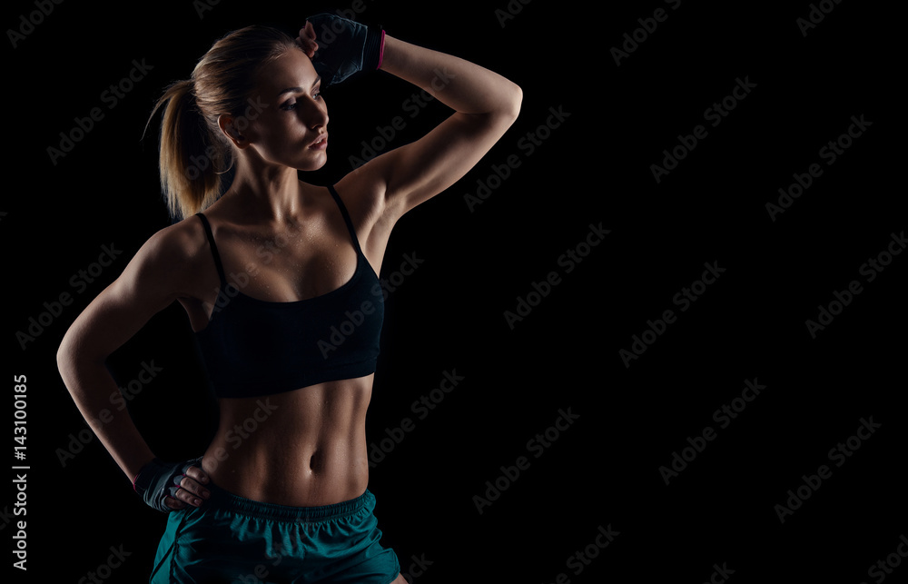 Sporty young girl in sportswear showing muscles on black background. Tanned young athletic woman. A great sport female body. Sporty young girl in sportswear showing muscles on black background. Tanned young athletic woman. A great sport female body.
