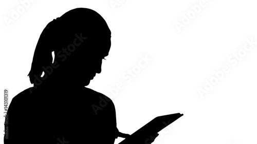 Silhouette Portrait of a young woman using a tablet.