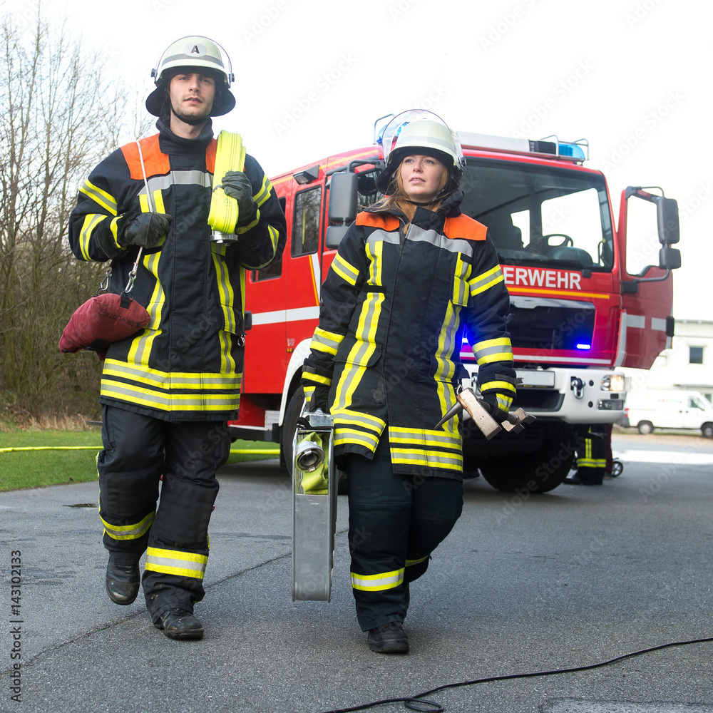 Feuerwehrmann und Feuerwehrfrau an einer Einsatzstelle Feuerwehrmann und Feuerwehrfrau an einer Einsatzstelle