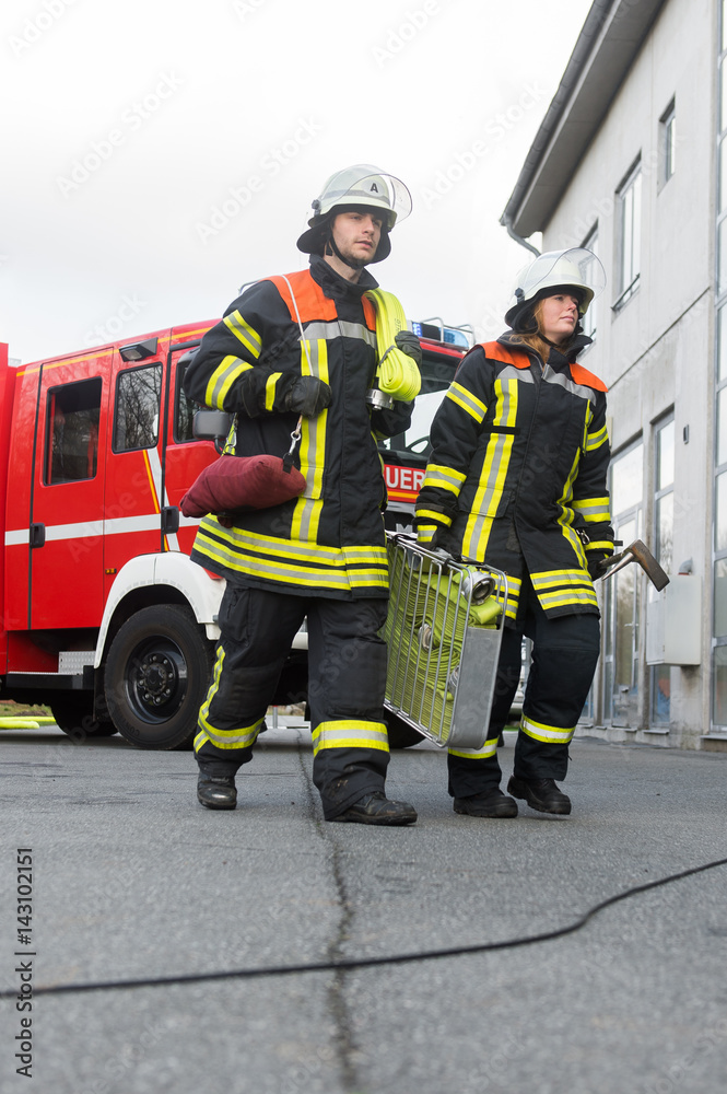 Feuerwehrmann und Feuerwehrfrau an einer Einsatzstelle Feuerwehrmann und Feuerwehrfrau an einer Einsatzstelle