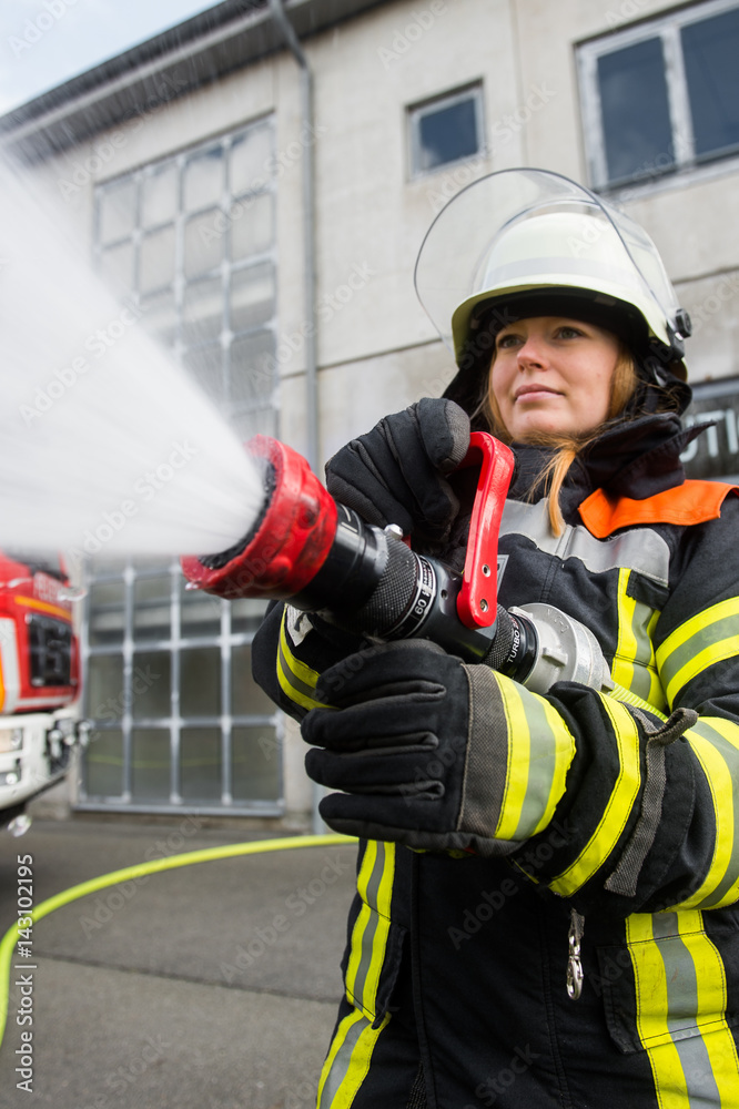 Fototapeta premium Junge Feuerwehrfrau löscht ein Feuer