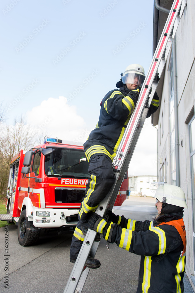 Feuerwehrmann kletter eine Leiter hoch, ein anderer sichert diese Stock  Photo | Adobe Stock
