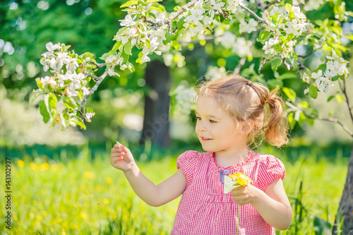 Happy little girl playing in spring apple tree garden