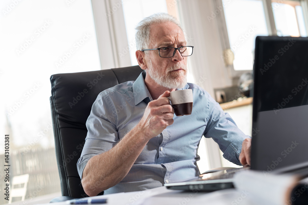 Portrait of senior businessman working on laptop, hard light Portrait of senior businessman working on laptop, hard light