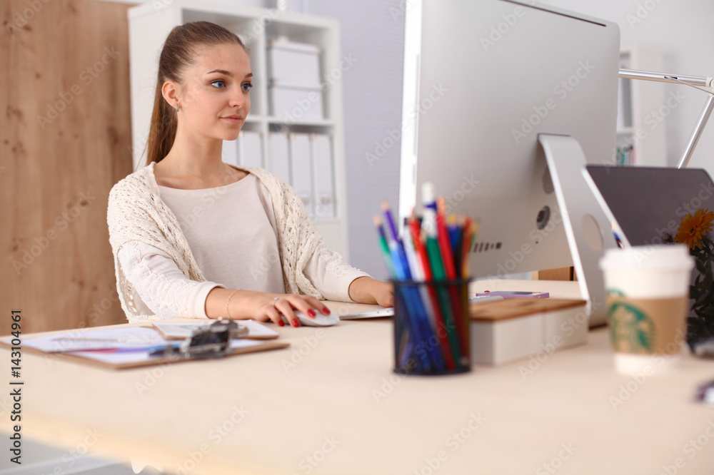 Young woman working in office, sitting at desk Young woman working in office, sitting at desk