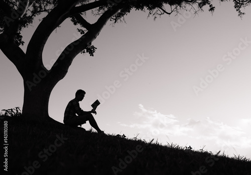 Young man reading a book in the park. 