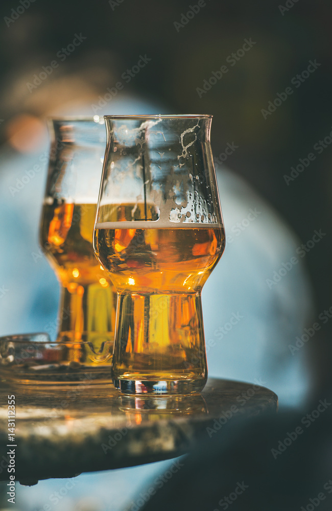 Two glasses of beer on a table in a street cafe, selective focus, vertical composition Two glasses of beer on a table in a street cafe, selective focus, vertical composition