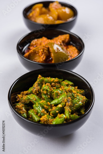 Group photograph of indian pickles like mango pickle , lemon pickle and green chilli pickle, sarved in ceramic bowls, selective focus photo