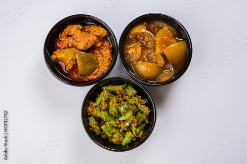 Group photograph of indian pickles like mango pickle , lemon pickle and green chilli pickle, sarved in ceramic bowls, selective focus
