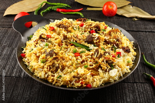 Homemade delicious mutton dum biriyani or pilaf served in cast iron cookware.