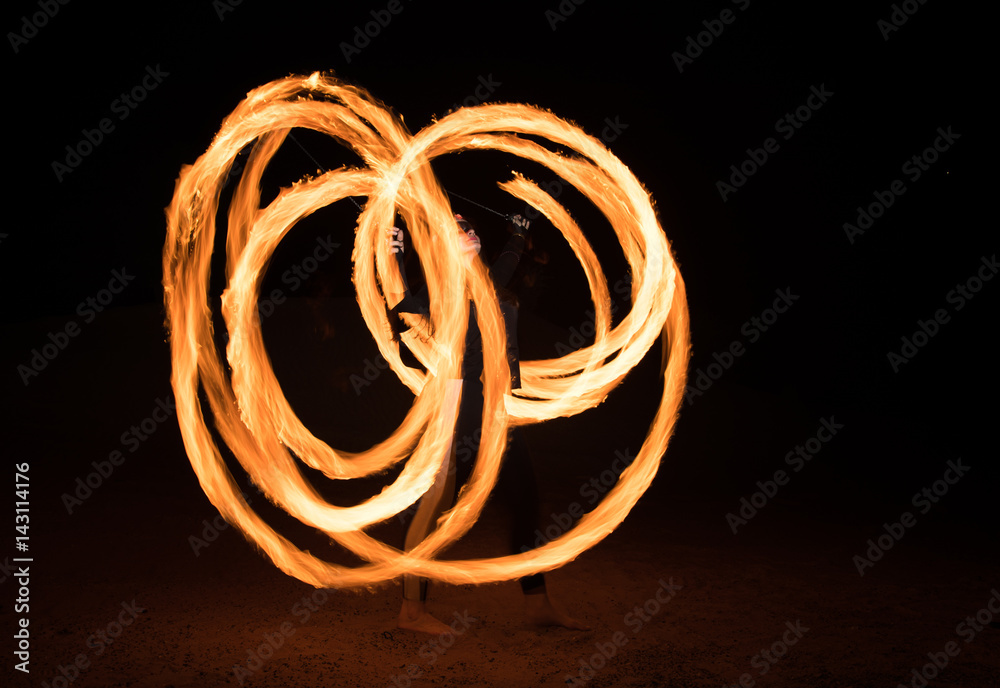 Dancer with flaming fire pois after dark.