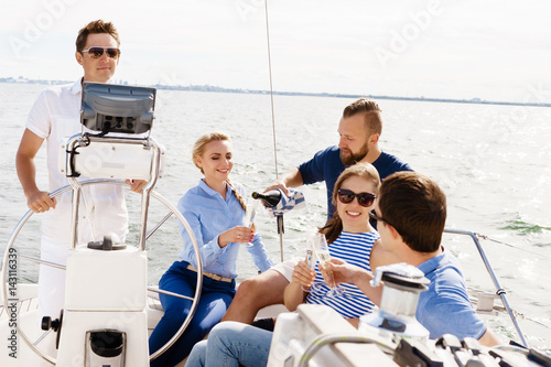 Photography Group of happy friends having a party on a yacht and drinking champagne
