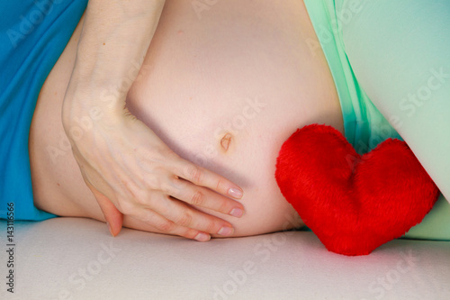 Pregnant woman lying on couch touching her belly