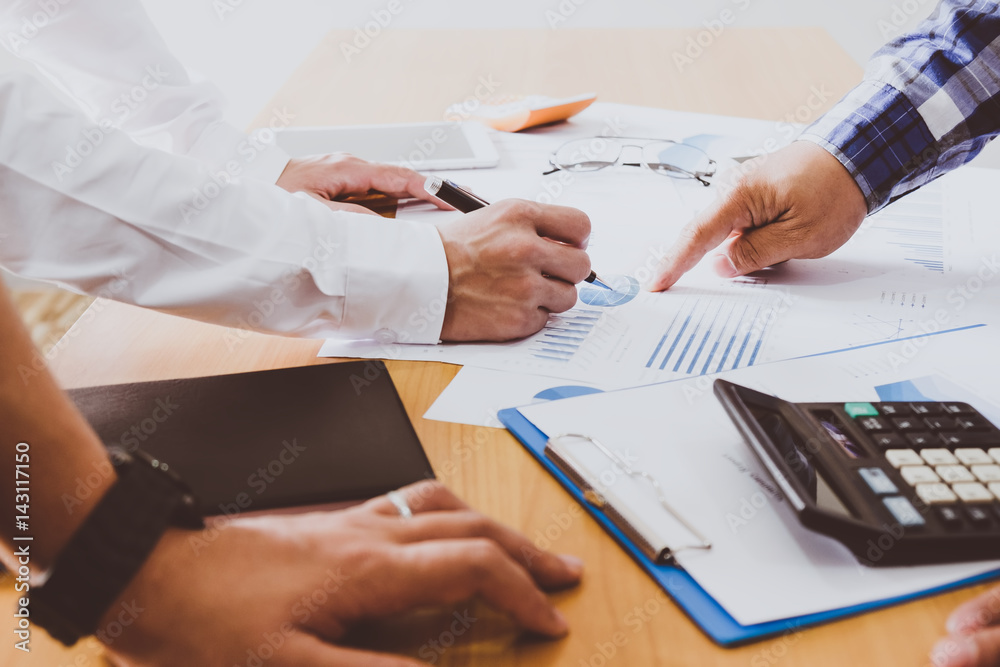 Business people brainstorming at office desk, they are analyzing financial reports and pointing out financial data on a sheet