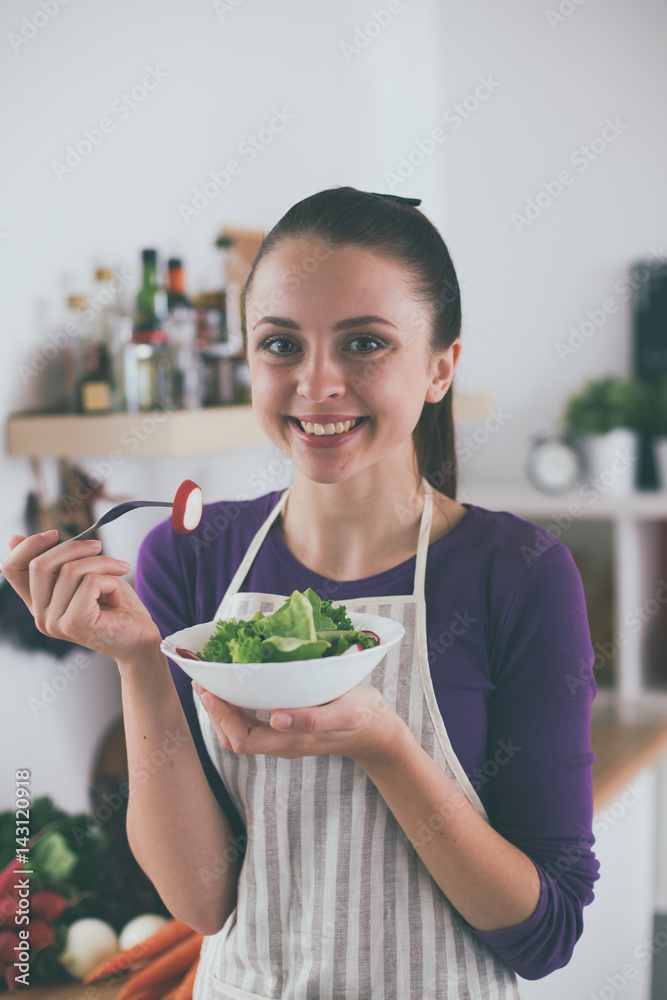 Young woman eating fresh salad in modern kitchen Young woman eating fresh salad in modern kitchen