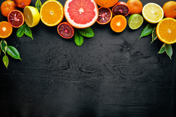 Fresh citrus fruits. Lemon orange, tangerine, lime. On a black background Wooden. Top view.
