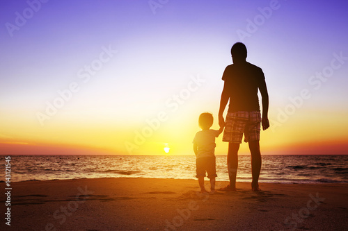 Father and son at sunset beach
