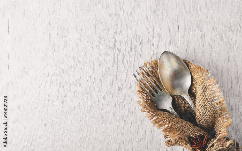 Obraz premium Cutlery, spoon and fork in old fabric on Wooden background. Top view. Free space.