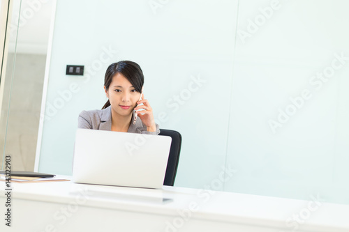 Businesswoman talk to cellphone and working on laptop computer at office