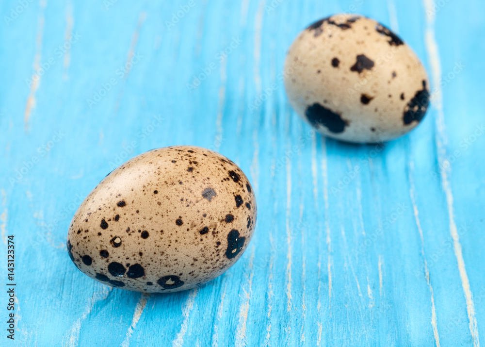 Obraz premium Two fresh quail eggs on a blue wooden background