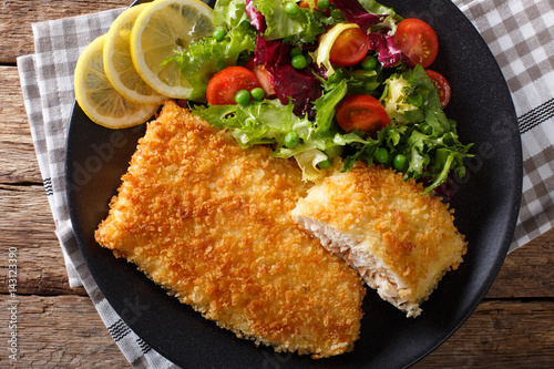 Photography Fried fish fillet in breading and fresh vegetable salad close-up
