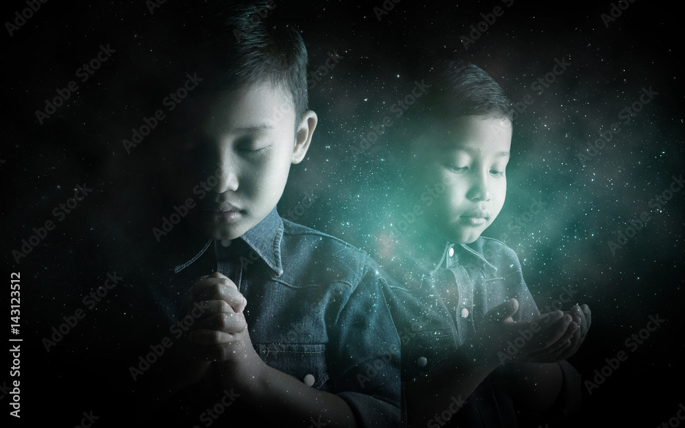 Little boy praying and praising God with stardust background.