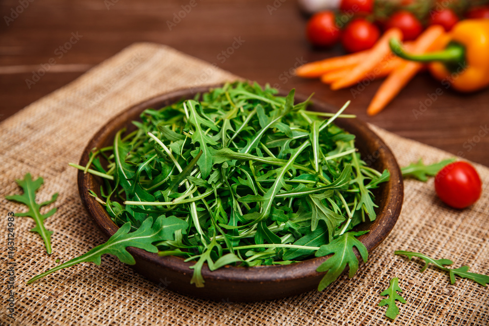Arugula leaves in bowl. Fresh salad. Carrot, pepper and cherry tomatoes. Natural raw vegetables. Organic bio food on rustic wooden table. Arugula leaves in bowl. Fresh salad. Carrot, pepper and cherry tomatoes. Natural raw vegetables. Organic bio food on rustic wooden table.