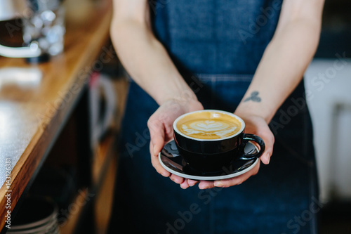 female barista holding cup of cappuccino. Close up.