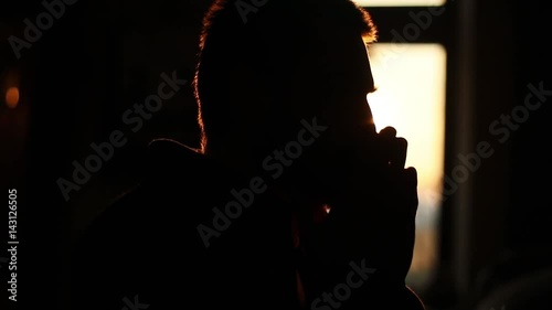 The dark close-up portrait of the upset and depressed man at the sunset background. photo