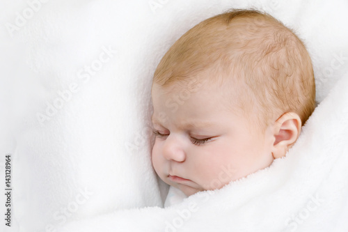 Cute little newborn baby girl sleeping wrapped in blanket
