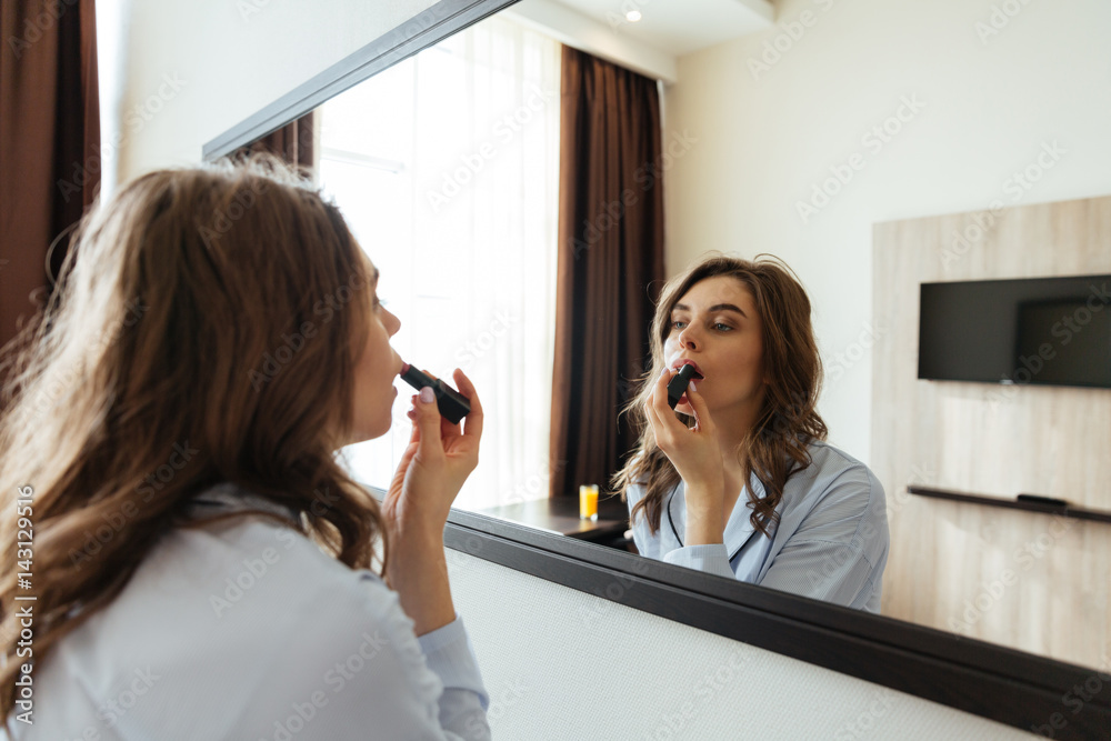 Сoncentrated young lady do makeup with lipstick Сoncentrated young lady do makeup with lipstick