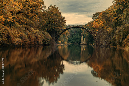 Autumn, cloudy evening over Devil's bridge in the park Kromlau, Germany.Stylized photo on old, retro, vintage © Mike Mareen