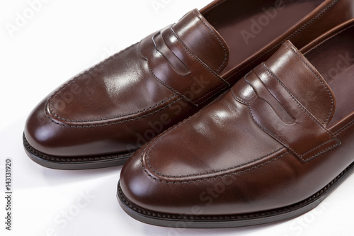 Footwear Concepts. Extreme Closeup of Leather Stylish Brown Penny Loafer Shoes Together Against White Background.