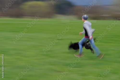 Junge Frau läuft mit ihrem Labradormischling über eine Wiese