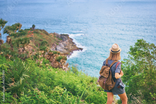 Travel concept. Young woman with camera and rucksack enjoying the sea view.