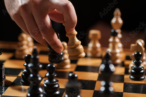 Close up image of man who is making move in chess game. 