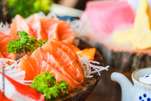 Close-up salmon raw sashimi on brown Japanese traditional dish on black table.