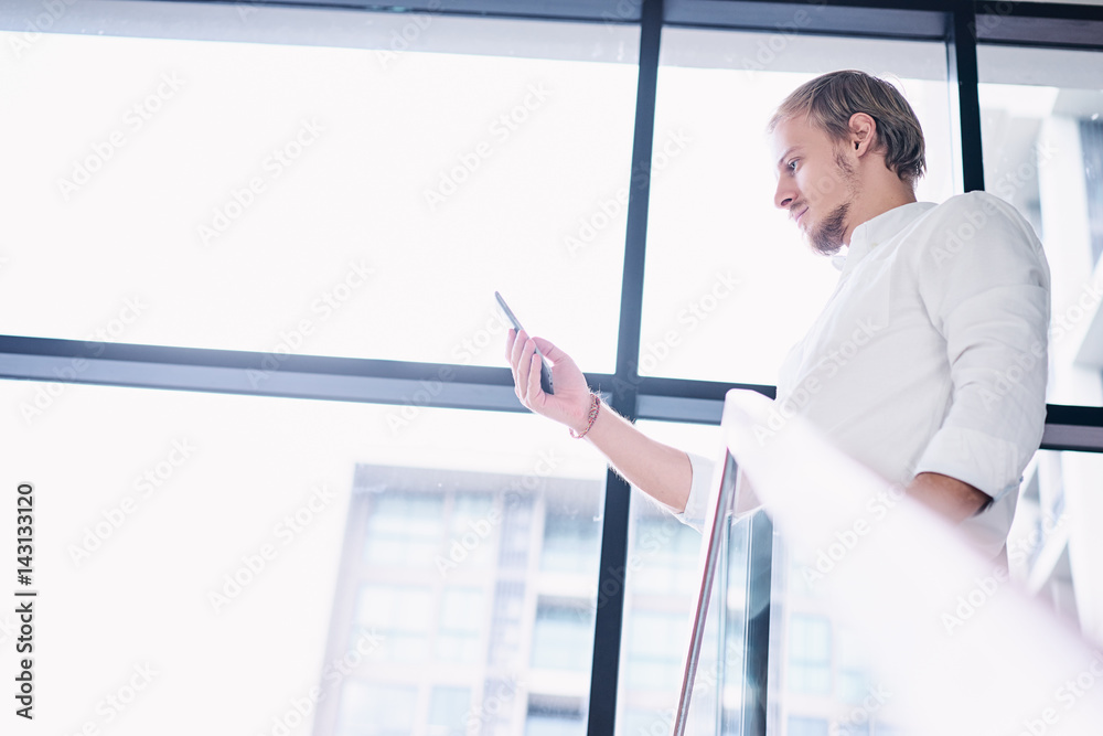 Fototapeta premium Business and technology. Handsome young man using smartphone in office.
