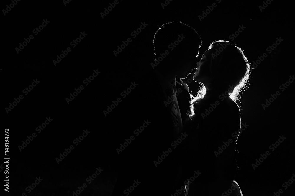 Silhouette of man and woman on a black background with back light, space for text