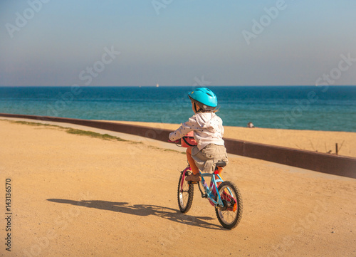 Little girl with her bike in the city near the sea shore