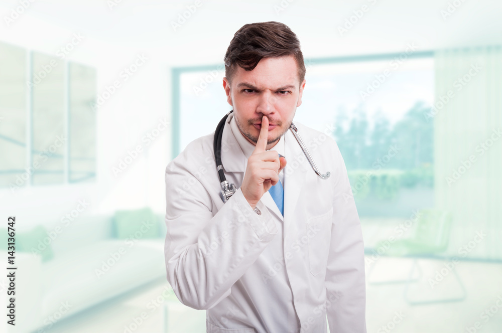Serious male doctor indicate to keep silence Serious male doctor indicate to keep silence