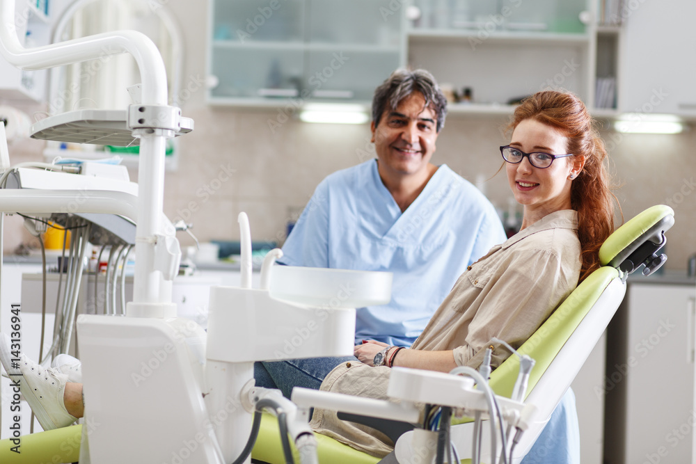 Obraz premium Senior male dentist in dental office talking with female patient and preparing for treatment.