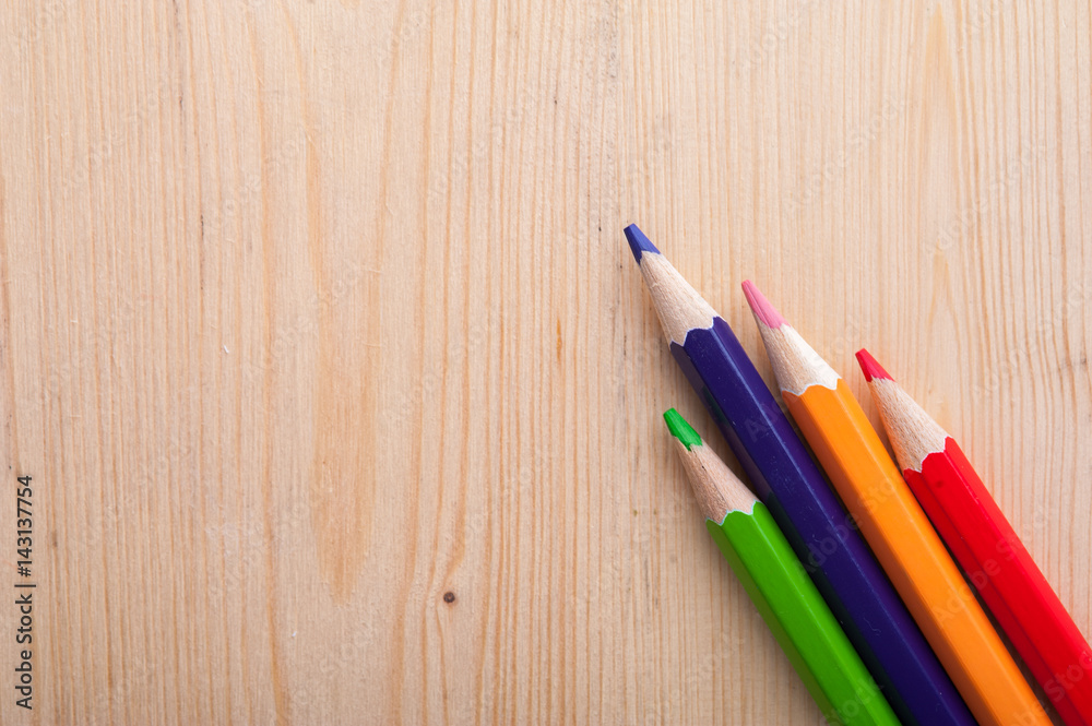 Four colorful pencils on wooden table