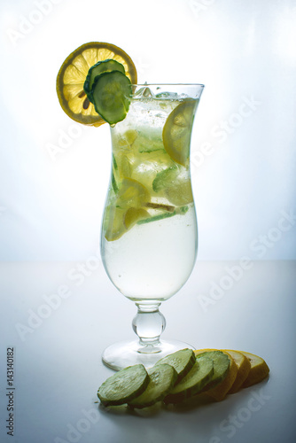 Fruit lemonade in hurricane glass with lemon and cucumber.
