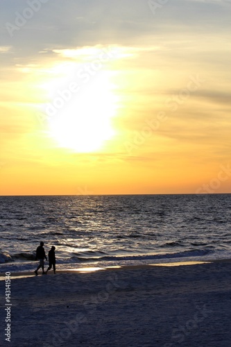 Pärchen spaziert am Strand bei Sonnenuntergang