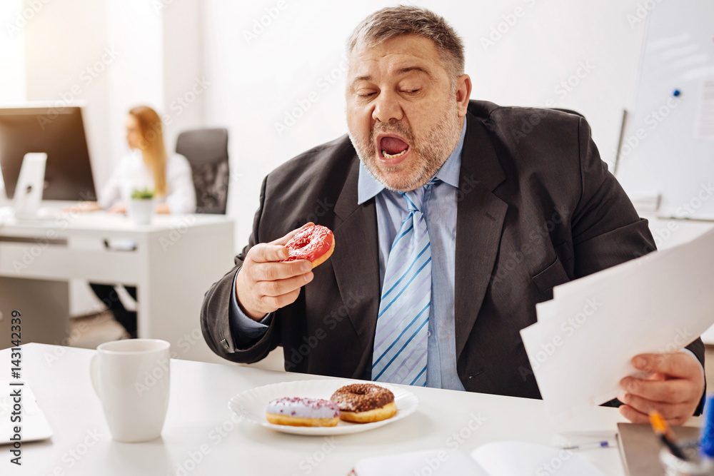 Hilarious chubby employee having a lunch during a busy week Hilarious chubby employee having a lunch during a busy week