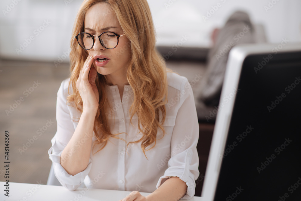 Frustrated young secretary suffering from aching teeth in the office Frustrated young secretary suffering from aching teeth in the office